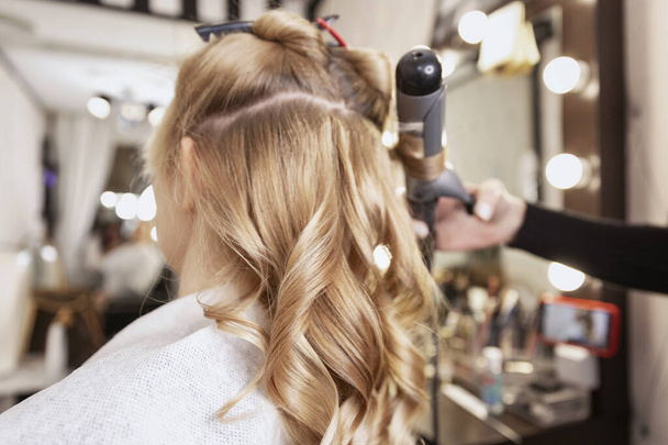 Blonde girl in a beauty salon doing a hairstyle. Close-up. - Photo, Image