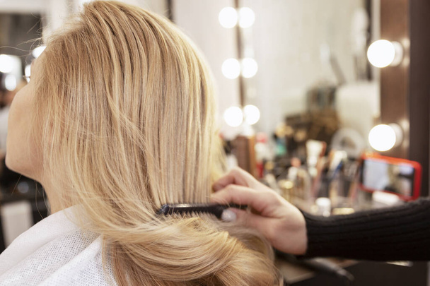 Blonde girl in a beauty salon doing a hairstyle. Close-up. - Photo, Image
