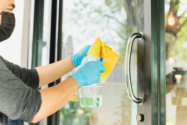 Hombre camarero manos con alcohol desinfectante puerta perilla prevenir el virus y las bacterias en la cafetería
 - Foto, imagen