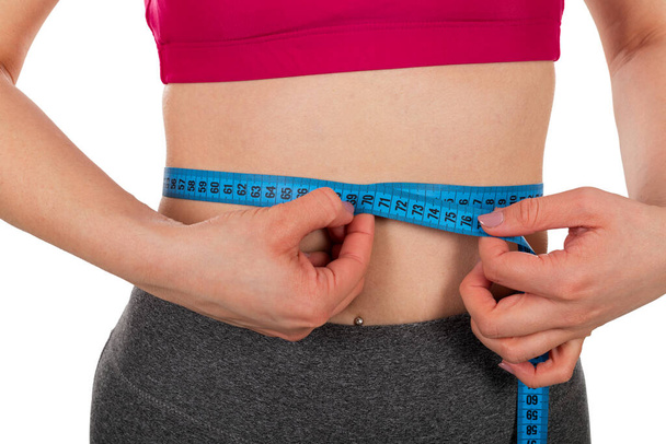 Genç kadınların bel ölçüleri, izole edilmiş arka planda bir mezura - kilo kaybı, diyet, vücut şekillendirme konsepti - Fotoğraf, Görsel