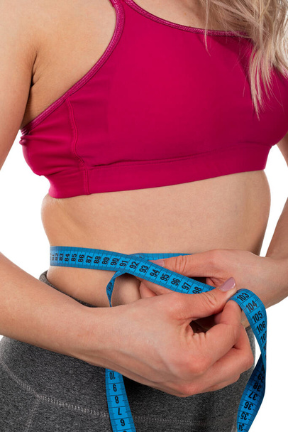 Tour de taille des jeunes femmes, tenant un ruban à mesurer sur fond isolé - perte de poids, régime alimentaire, concept de mise en forme du corps
 - Photo, image