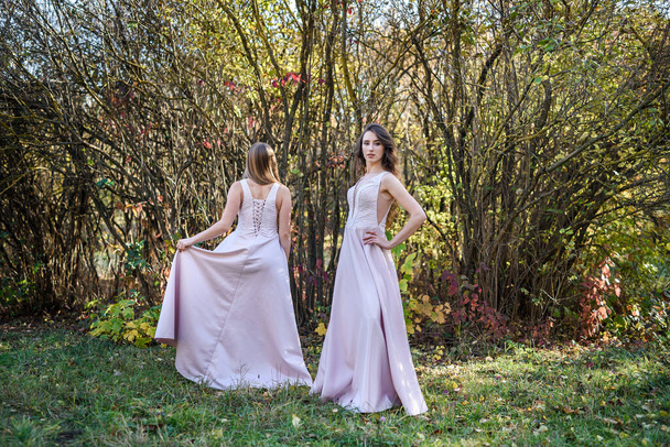 Δύο νεαρές πριγκίπισσες με ωραίο μπεζ φόρεμα στο φθινόπωρο πάρκο. Φωτογραφία μόδας. - Φωτογραφία, εικόνα