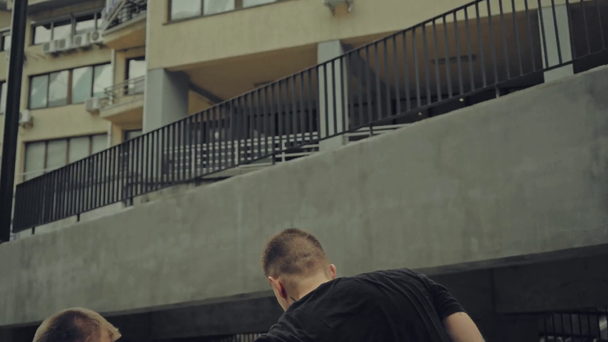 επιθετικοί άνδρες που μάχονται στο δρόμο κοντά στο κτίριο  - Πλάνα, βίντεο