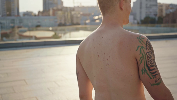 bez koszulki mężczyzna z tatuażami uśmiechający się i trzymający nunchaku  - Materiał filmowy, wideo