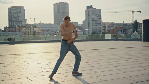 Hemdloser Mann in Jeans Schwerttanz  - Filmmaterial, Video