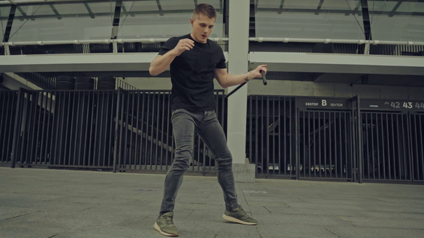 wytatuowany mężczyzna ćwiczący z nunchaku na ulicy  - Materiał filmowy, wideo