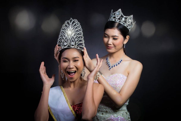 Минулого року переможниця конкурсу Miss Beauty Pageant Contest поставила діамантову корону на останній конкурс Miss Beauty Queen Pageant Contest з почуттям усмішки радісний вираз обличчя, дві азійські жінки момент сесії - Фото, зображення