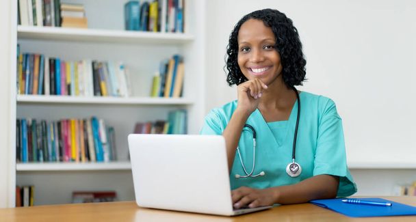 Laughing african american female doctor answering questions of patient online at hospital - Foto, imagen