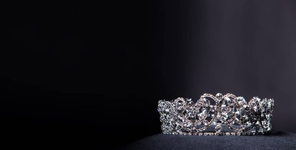 Diamond Silver Crown for Miss Pageant Beauty Contest, Crystal Tiara jewelry decorated gems stone and abstract dark background on black velvet fabric cloth, Macro photography copy space for text logo - Photo, Image