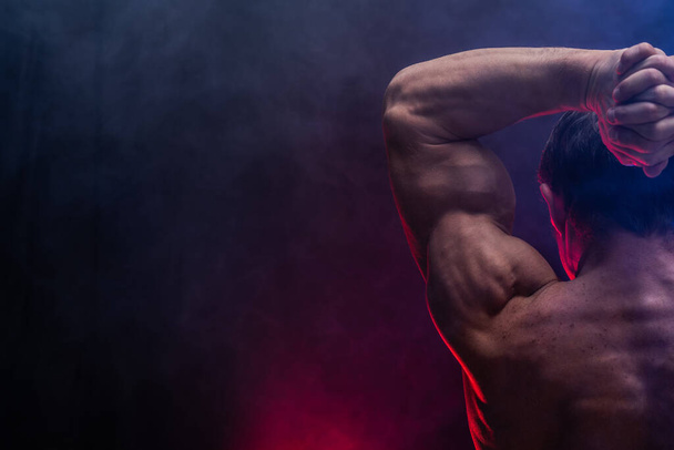Muscular man showing muscles isolated on the black background close up. Concept of healthy lifestyle  - Zdjęcie, obraz