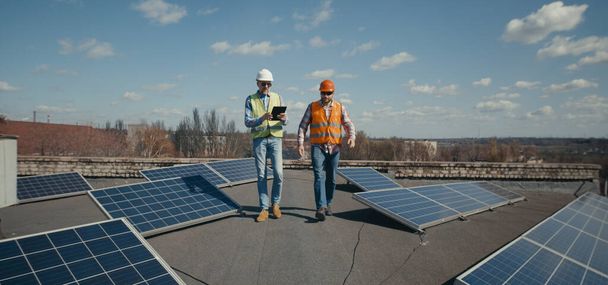 Ingeniero y técnico discutiendo entre paneles solares
 - Foto, imagen