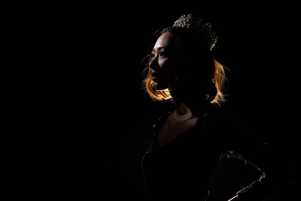 "Portrait Silhouette Shadow Back Rim Light of Miss Pageant Beauty Queen Contest" "Silver Diamond Crown", яка виражає посмішку, темне чорне тло студії, крик від радості до камери. - Фото, зображення