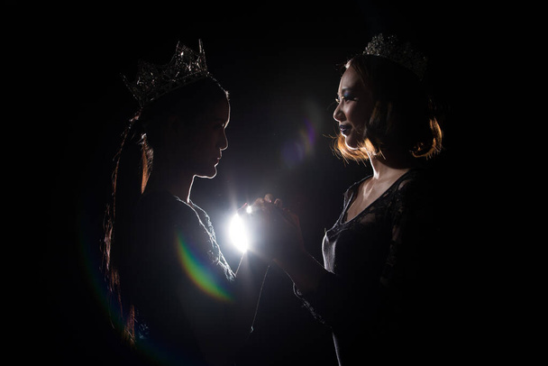 Zwei Silhouette Shadow Back Rim Light of Miss Pageant Schönheitskönigin-Wettbewerb mit Silver Diamond Crown halten zusammen beten für den letzten Moment verkünden Gewinner Preis, Studio Beleuchtung dunkelschwarzen Hintergrund - Foto, Bild