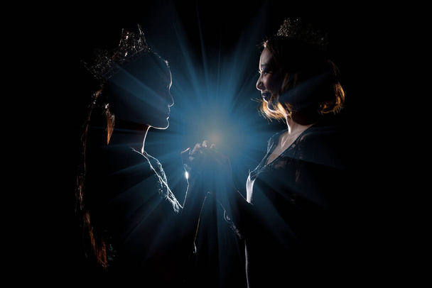 Két Silhouette Shadow Back Rim Light of Miss Pageant Szépségkirálynő Verseny Ezüst Gyémánt Korona tartsa össze imát az utolsó pillanatban jelenti be a győztes díjat, stúdió világítás sötét fekete háttér - Fotó, kép