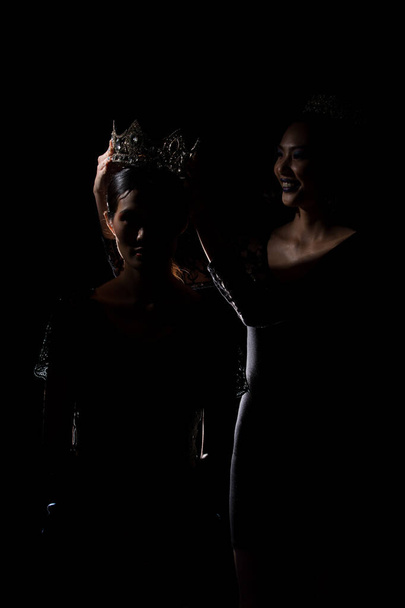 Két Silhouette Shadow Back Rim Light of Miss Pageant Beauty Queen Contest helyezte Silver Diamond Crown a győztes utolsó pillanatban legszebb nő a világ univerzumában, stúdió világítás sötét fekete háttér - Fotó, kép