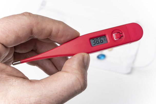 Männliche Hand hält ein Thermometer mit einer hohen Temperatur. Grippezeit. - Foto, Bild