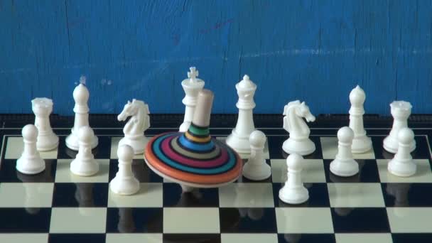 A sakktábla fehér chessmens, színes búgócsiga - Felvétel, videó