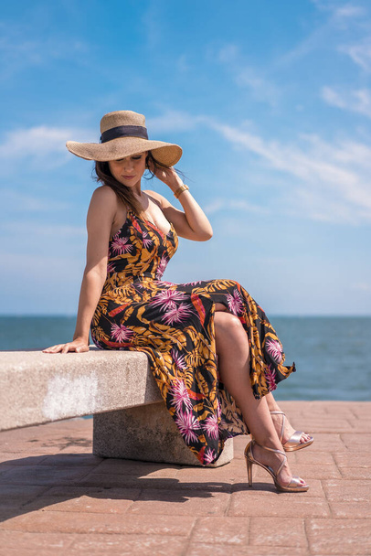 beautiful young woman wearing summer dress and straw hat on the beach - Foto, Imagem
