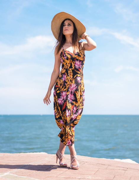 beautiful young woman wearing summer dress and straw hat on the beach - Φωτογραφία, εικόνα