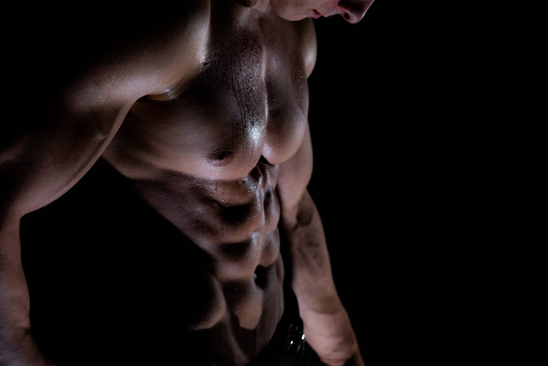 Muscular man showing muscles isolated on black background. healthy lifestyle  - Zdjęcie, obraz