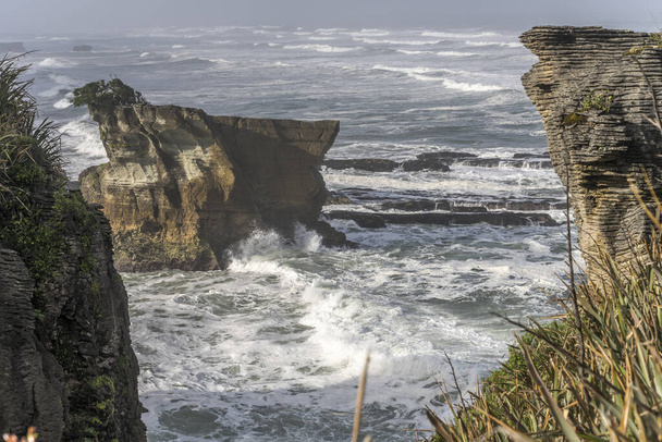 platy desgastou o penhasco e ondas do mar de Tasman na costa, disparado na luz brilhante da mola em Punakaiki, costa ocidental, ilha sul, Nova Zelândia
 - Foto, Imagem