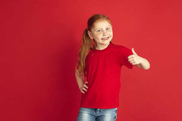 Caucasian little girl portrait isolated on red studio background, emotions concept - 写真・画像