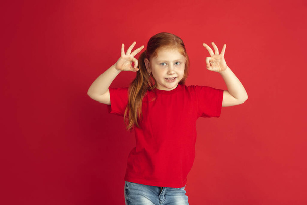 Caucasian little girl portrait isolated on red studio background, emotions concept - Foto, Imagen