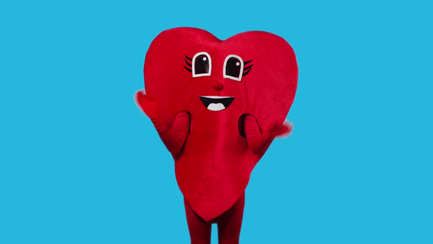 person in heart costume waving hands isolated on blue - Footage, Video