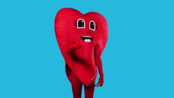 osoba v kostýmu srdce drží luk a šíp izolované na modré - Záběry, video