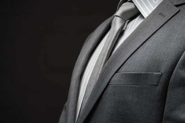 πορτρέτο επιχειρηματίας ντυμένος με γκρι κοστούμι, σκούρο φόντο τοίχο - Φωτογραφία, εικόνα