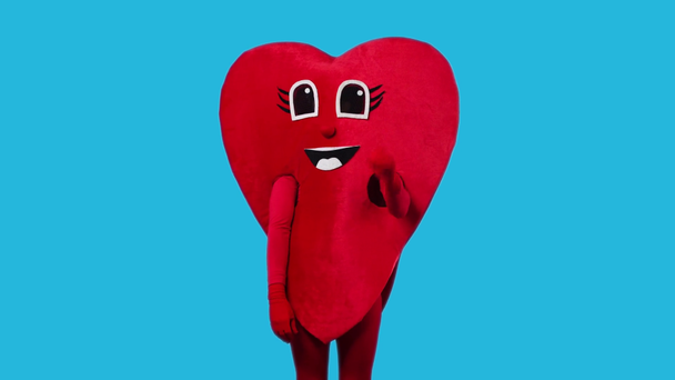 person in heart costume showing ok gesture isolated on blue - Footage, Video