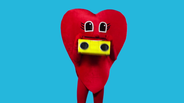 person in heart costume dancing with boombox isolated on blue - Πλάνα, βίντεο