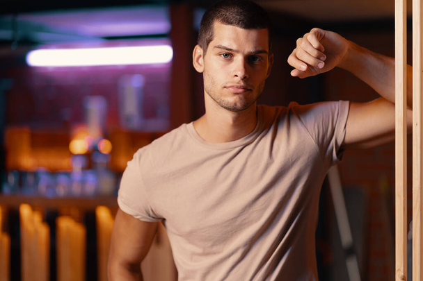 Close-up portret van aantrekkelijk mannelijk model. Retro Wave portret van een jonge man in een bar. Model in kleurrijke felle neonlichten. - Foto, afbeelding