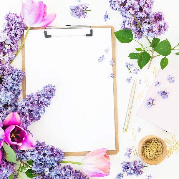 Samenstelling met klembord, pen, takken van lila bloemen op witte achtergrond. Vlakke plaat - Foto, afbeelding