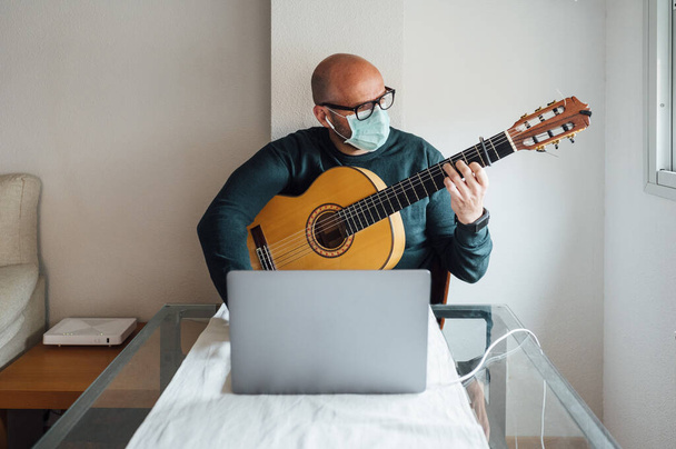 Człowiek uczy się grać na gitarze online podczas kwarantanny - Zdjęcie, obraz