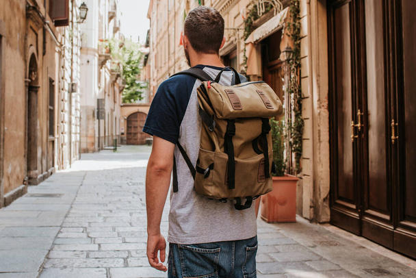 A man with a backpack walks through the streets of the city. Tourist enjoy holidays in Europe. Beautiful old historical architecture. Italian weekend. Travel to Turin, Italy. Adventure lifestyle - Photo, image