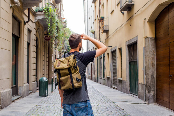 A man with a backpack walks through the streets of the city. Tourist enjoy holidays in Europe. Beautiful old historical architecture. Italian weekend. Travel to Turin, Italy. Adventure lifestyle - Foto, immagini