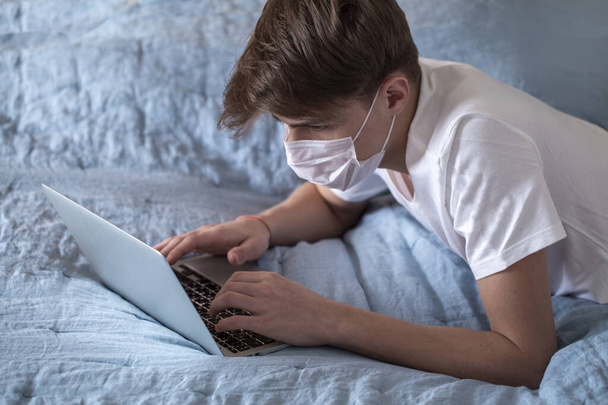Doma vyučovaný teenager v masce kvůli viru korony. pracovat v karanténě doma - Fotografie, Obrázek