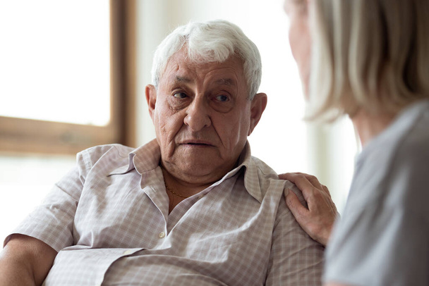 Жінка середнього віку, що підтримує засмученого літнього чоловіка, торкається плеча
 - Фото, зображення
