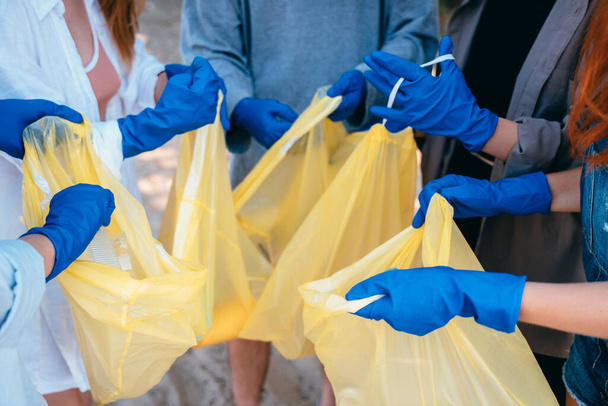 Группа друзей активистов собирает пластиковые отходы на пляже. Охрана окружающей среды
. - Фото, изображение