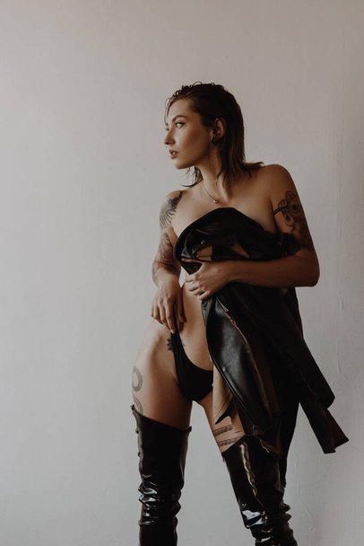 Sexy woman with tattoos wearing black bikini and leather jacket - Valokuva, kuva