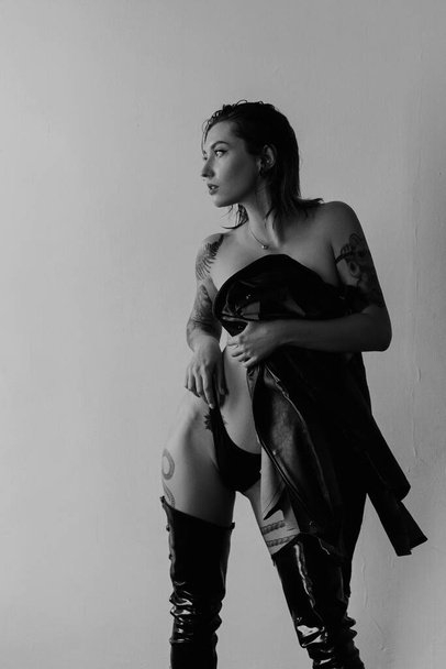 Sexy woman with tattoos wearing black bikini and leather jacket - Zdjęcie, obraz