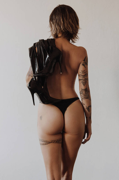 Back view of sexy woman with tattoos wearing black bikini - Photo, Image