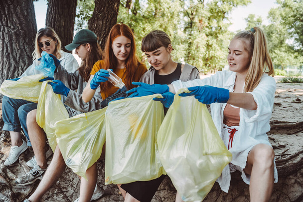 Grupa aktywistów zbierająca odpady z tworzyw sztucznych w parku. Ochrona środowiska. - Zdjęcie, obraz