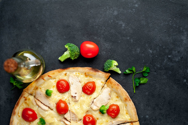 вид на запеченную домашнюю пиццу с куриным мясом, сыром и помидорами на фоне деревенского стола
 - Фото, изображение