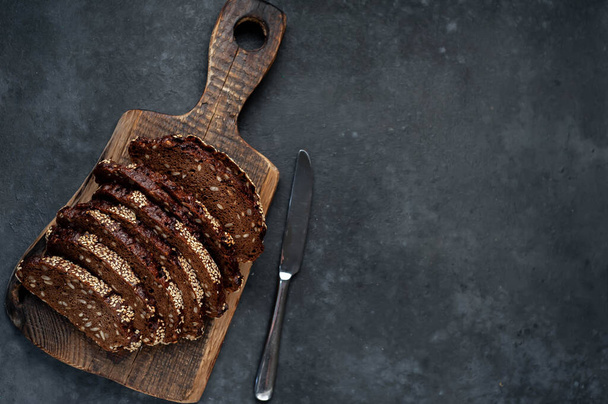rebanadas de pan de cereal horneado fresco en tablero de madera sobre fondo rústico
 - Foto, Imagen