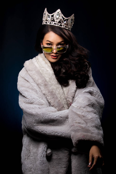 Portrait Miss Pageant beauty Contest in Asian Fur Gray winter jacket dress with Silver Diamond Crown Sash, fashion make up face hair style, studio lighting dark background bubble sunglasses - Foto, Imagen