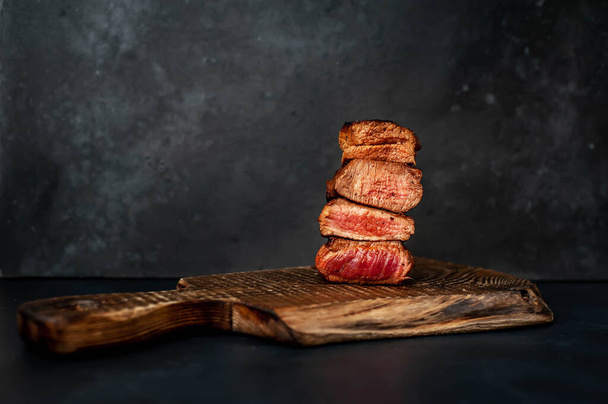 medium rare medallion steak slices on wooden board on gray rustic table background - Photo, Image