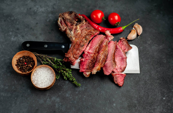 Grillezett New York szalag steak szeletek fűszerekkel és paradicsommal a levélvágó késen rusztikus asztal háttér - Fotó, kép