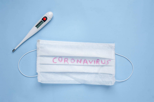 maschera medica con parole coronavirus e termometro isolato su sfondo blu
 - Foto, immagini